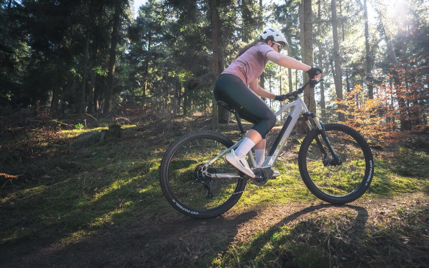A rider on an eBike riding a sunlit pine-forest trail near Costa da Caparica