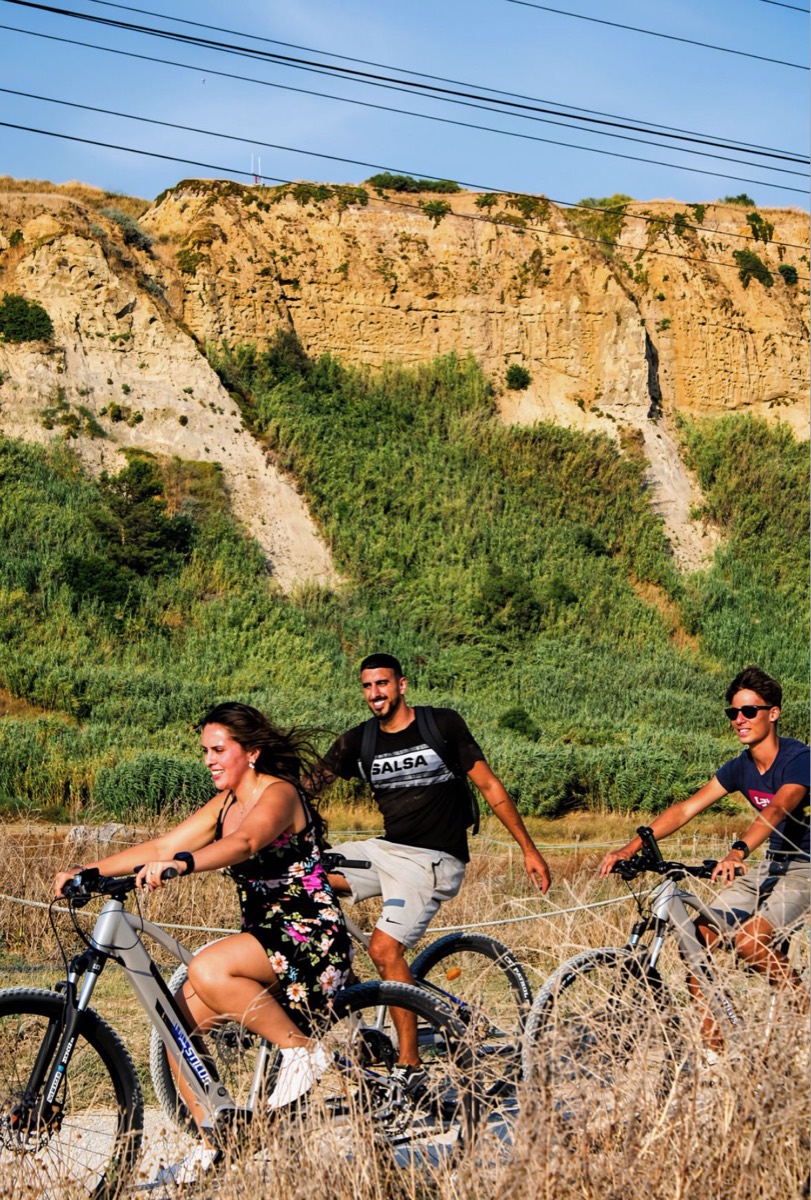 Three riders on eBikes on a trail below the fossil cliffs of Costa da Caparica