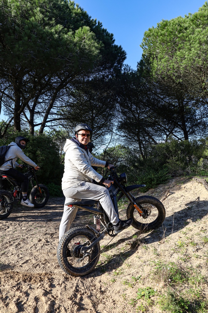 A rider on an all-terrain eBike on a sandy forest trail under umbrella pines during the Into the Woods adventure near Costa da Caparica