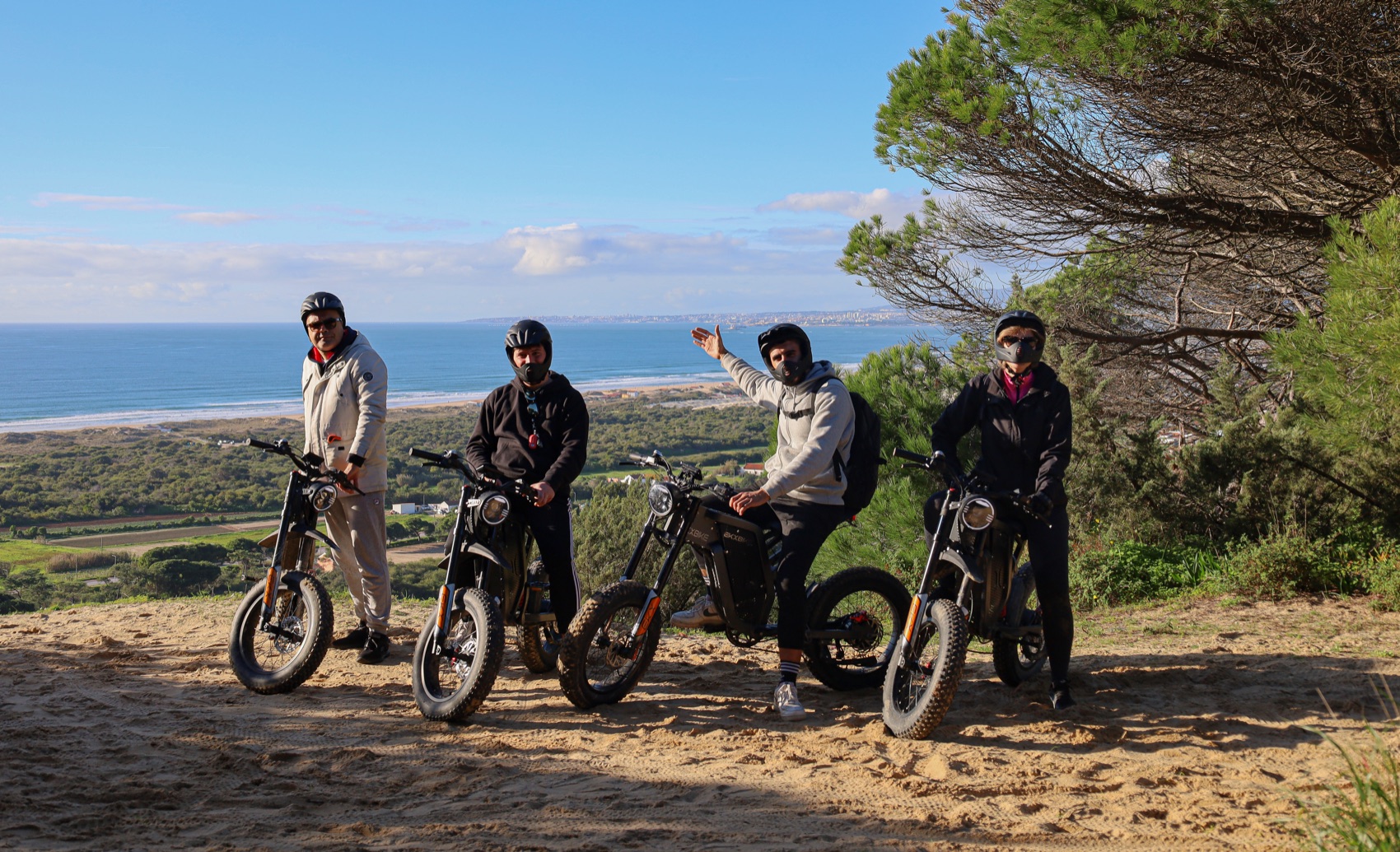 Four riders with all-terrain eBikes on a clifftop above the Atlantic coast at Costa da Caparica